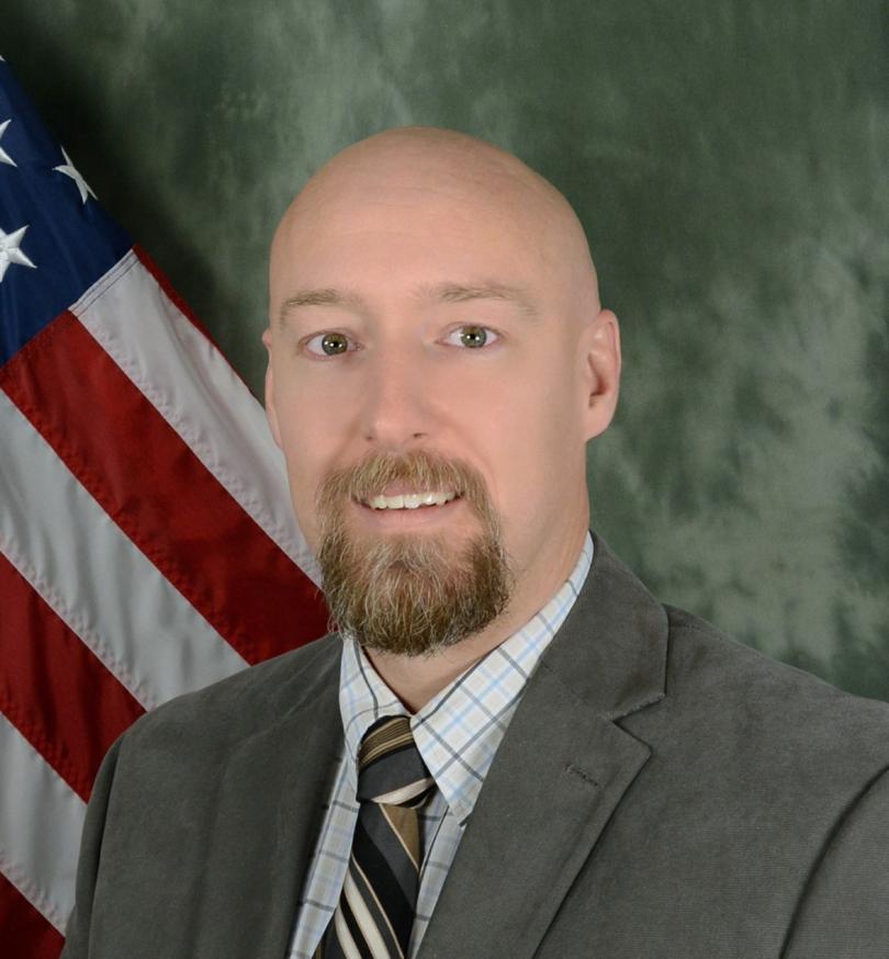 Color portrait of Joshua Kennedy with the American Flag in the background.
